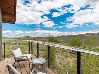 Enjoy breathtaking views from this stunning property! This home features a beautiful outdoor deck with comfortable seating, perfect for relaxing and taking in the scenery.