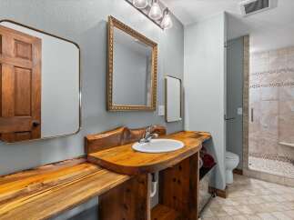 Step into this beautifully designed bathroom featuring a unique wooden vanity and a stylish mirror.