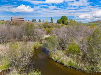 Discover the tranquility of this stunning property, featuring a serene river winding through lush greenery.