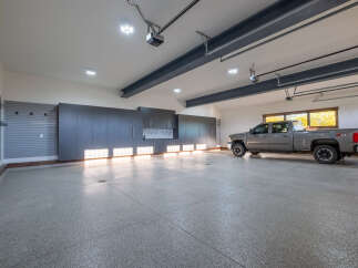 This spacious garage offers ample room for vehicles and storage, featuring sleek cabinetry and a durable epoxy floor.