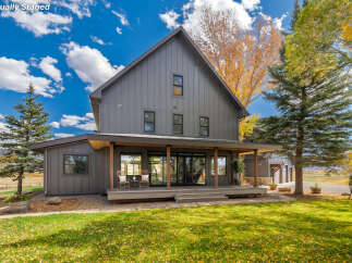 This stunning, modern farmhouse boasts a striking exterior with a covered porch and a spacious yard, perfect for outdoor living.