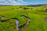 Experience the serene beauty of this sprawling ranch, featuring a winding creek and lush green pastures perfect for livestock or recreation.