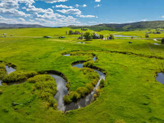 Experience the serene beauty of this sprawling ranch, featuring a winding creek and lush green pastures perfect for livestock or recreation.