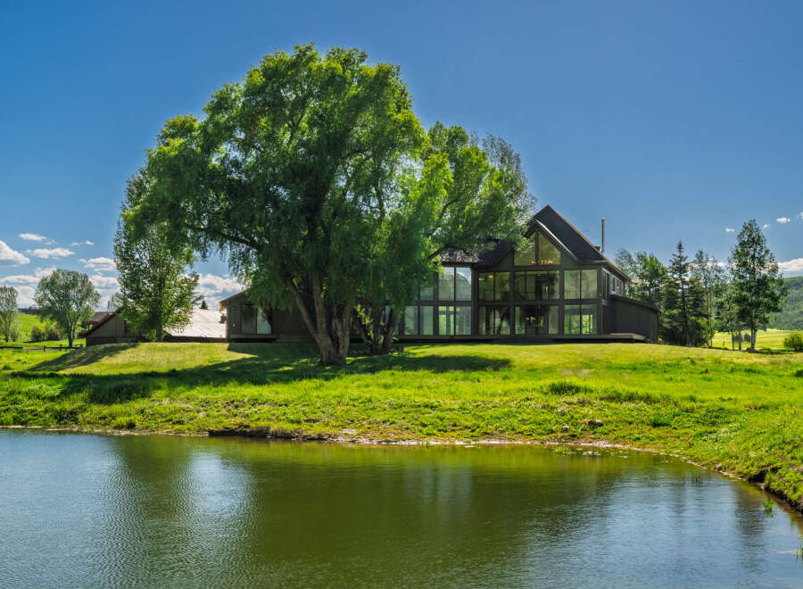 Experience luxury living in this stunning modern home, featuring expansive floor-to-ceiling windows that offer breathtaking views of the surrounding natural landscape.