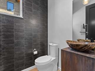 This stunning bathroom features a modern design with a unique dark tiled accent wall.