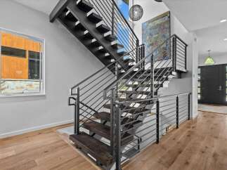 This stunning property boasts a modern staircase with sleek metal railings and dark wood steps, creating a striking focal point.