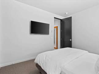 This modern bedroom boasts a sleek, minimalist design with a mounted flat-screen TV, perfect for entertainment.