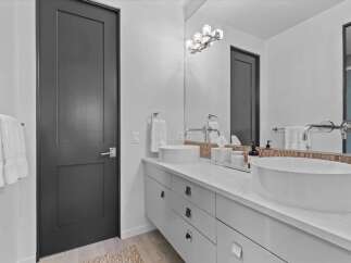 This modern bathroom features a sleek design with a dark gray door and a white vanity.