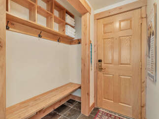 Step into this inviting entryway, featuring a custom-built wooden bench and storage shelves, perfect for organizing your belongings.