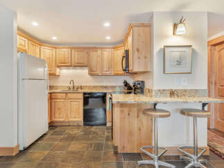 This charming kitchen boasts beautiful wooden cabinetry and a sleek black dishwasher, creating a warm and inviting atmosphere.