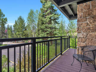 Enjoy the serene beauty of this property's balcony, offering stunning views of lush greenery and a clear blue sky.