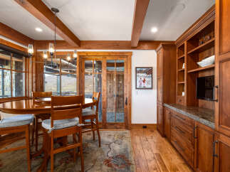 This stunning dining room boasts exquisite wooden beams and a charming chandelier, creating a warm and inviting atmosphere.