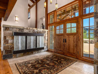Step into luxury with this stunning entryway, featuring a grand wooden door and elegant stone accents.