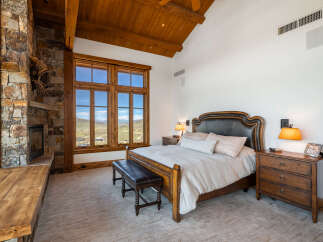 Experience luxury in this stunning bedroom featuring a cozy fireplace and expansive windows that frame breathtaking mountain views.