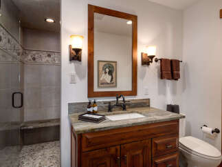 This stunning bathroom features a beautiful wooden vanity with a granite countertop, offering both style and functionality.