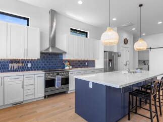 This stunning kitchen boasts a modern design with sleek white cabinetry and a striking blue backsplash.