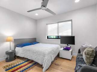 This modern bedroom offers a cozy retreat with its plush, white bedding and stylish decor.