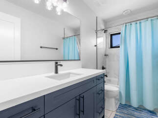 This modern bathroom boasts a sleek design with a navy blue vanity and a pristine white countertop.