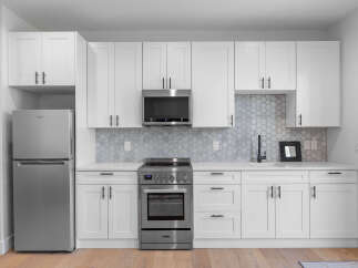 This modern kitchen boasts sleek white cabinetry, stainless steel appliances, and a stylish backsplash.