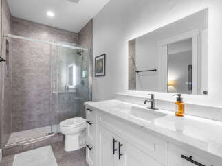 Step into a luxurious bathroom retreat! This stunning space features a modern vanity with sleek black hardware and a pristine white countertop.