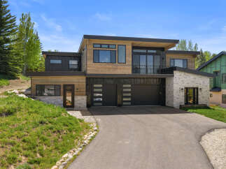 This stunning modern home boasts a sleek design with a combination of wood and dark accents.
