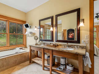 This luxurious bathroom features a double vanity with a stunning granite countertop and elegant wooden cabinetry.