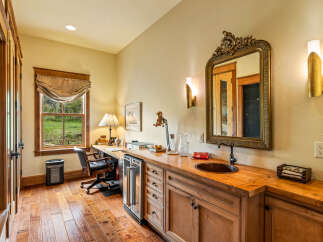 This stunning home office boasts a luxurious design with rich wooden accents and a built-in bar area.