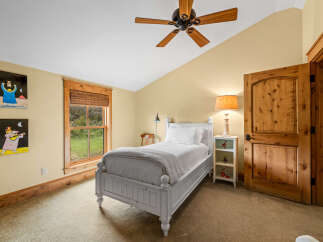 This charming bedroom features a cozy, white bed and a warm, inviting color palette.