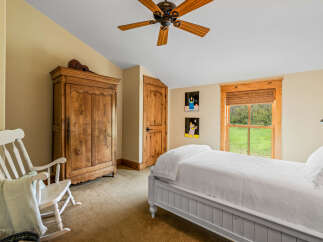 This charming bedroom features a cozy ambiance with a wooden wardrobe and a rocking chair.
