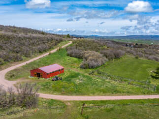 Discover the charm of this stunning rural property, featuring a vibrant red barn and a winding dirt road that leads to endless possibilities.