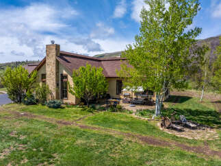 This stunning property boasts a beautiful exterior with a stone chimney and a well-maintained lawn.