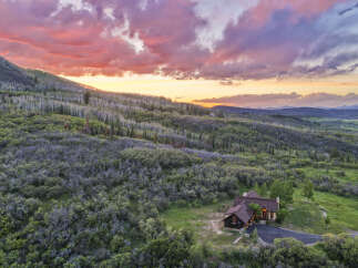 Experience breathtaking sunset views from this stunning mountain home, nestled amidst lush greenery and rolling hills.