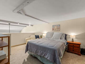 This cozy bedroom features a comfortable bed with soft bedding and a charming mountain-themed artwork.