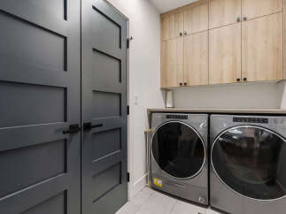 This modern laundry room features sleek, gray doors and a matching washer and dryer set.