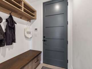 Step into this inviting entryway, showcasing a modern design with a sleek, gray door and a built-in wooden bench.