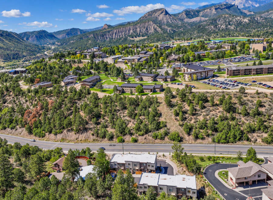 Discover this stunning aerial view of a sprawling university campus nestled amidst majestic mountains and lush green forests.