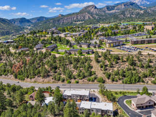 Discover this stunning aerial view of a sprawling university campus nestled amidst majestic mountains and lush green forests.