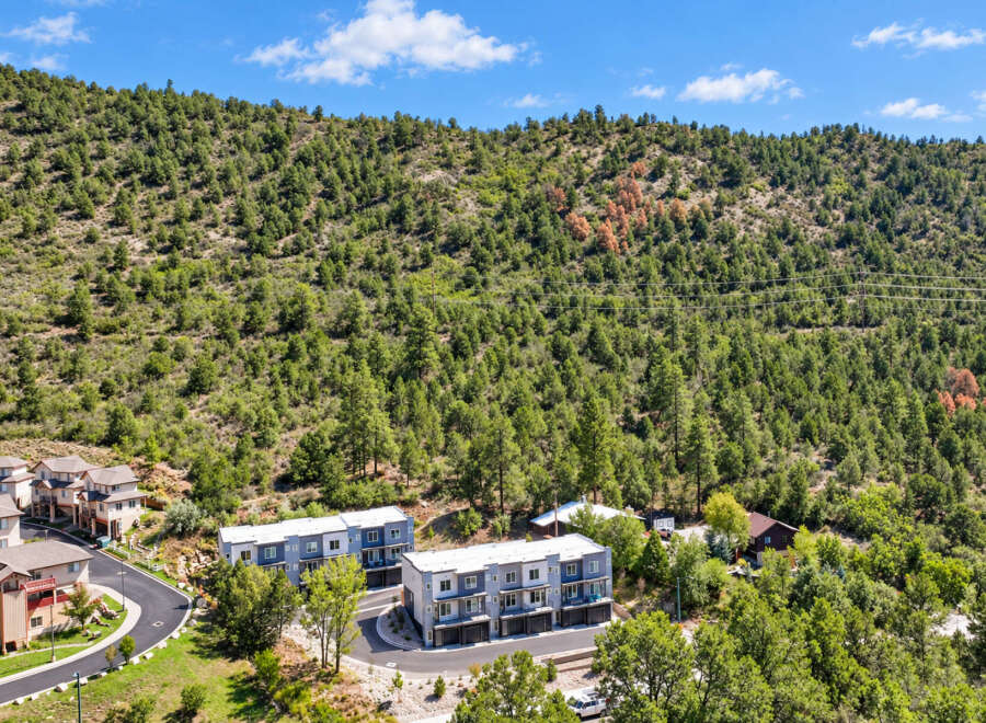 Discover modern living nestled against a backdrop of lush green hills and a clear blue sky.