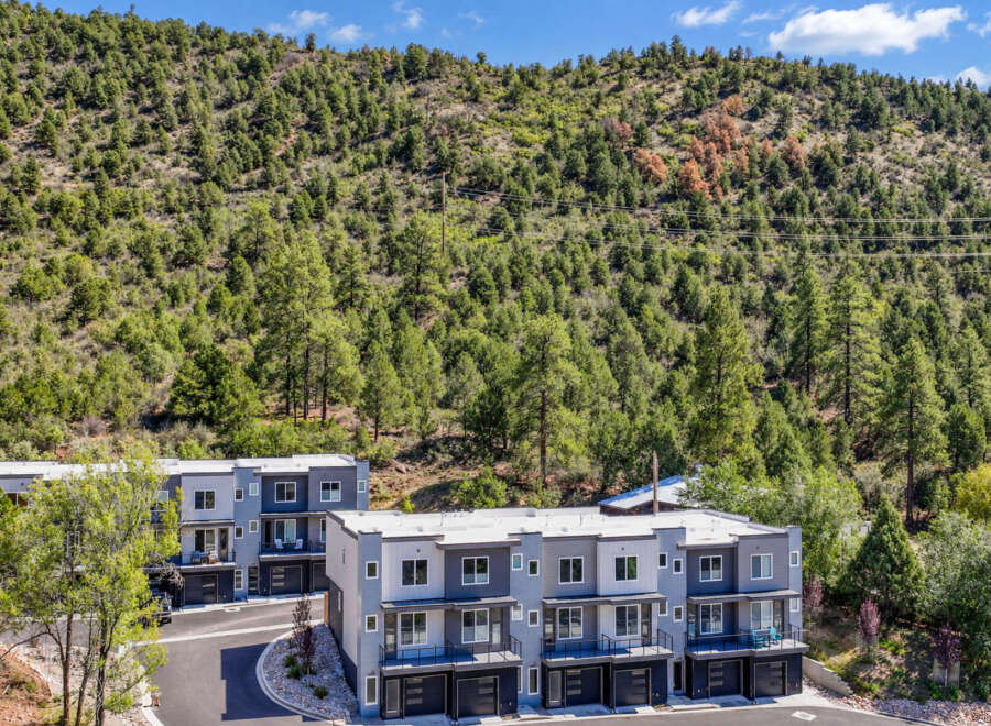 Discover modern living in this stunning townhouse complex nestled against a backdrop of lush green hills.