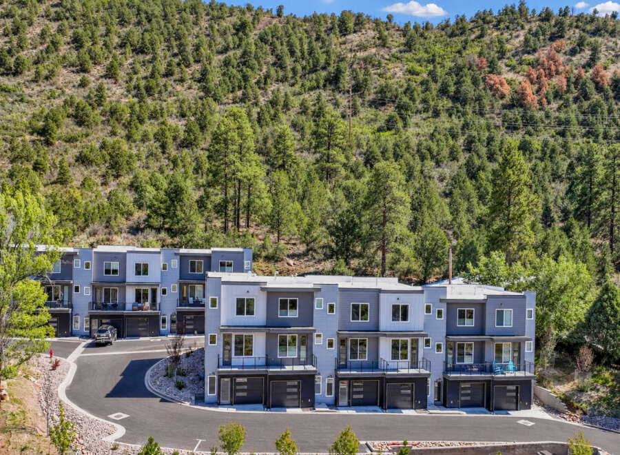 Discover modern living in this stunning townhouse complex nestled against a backdrop of lush green hills.
