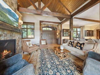 Experience luxury living in this stunning property, featuring a grand living room with a stone fireplace and exposed wooden beams.