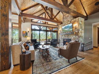 Experience luxury living in this stunning home featuring a grand living room with exposed wooden beams and a stone fireplace.
