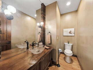 Step into luxury with this stunning bathroom featuring a unique wooden vanity and elegant glass sinks.