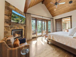 Experience luxury living in this stunning bedroom featuring a cozy fireplace and a large-screen TV.