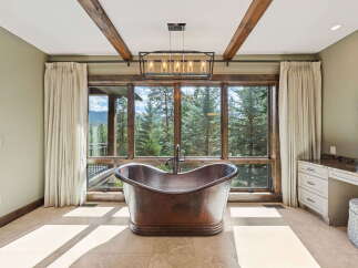 Indulge in luxury with this stunning bathroom, featuring a copper bathtub and breathtaking views of the surrounding nature.