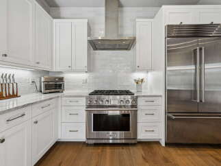 This stunning kitchen boasts modern elegance with its pristine white cabinetry and sleek stainless steel appliances.