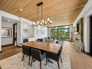Experience luxury living in this stunning property featuring a spacious dining area with a modern chandelier and a beautiful wooden table.