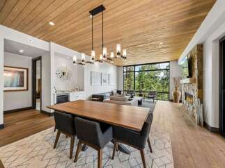 Experience luxury living in this stunning property featuring a spacious dining area with a modern chandelier and a beautiful wooden table.