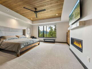 Experience luxury in this stunning bedroom featuring a modern fireplace and a large flat-screen TV.