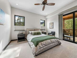Step into luxury with this stunning bedroom featuring a plush bed, a cozy green throw, and a stylish ceiling fan.